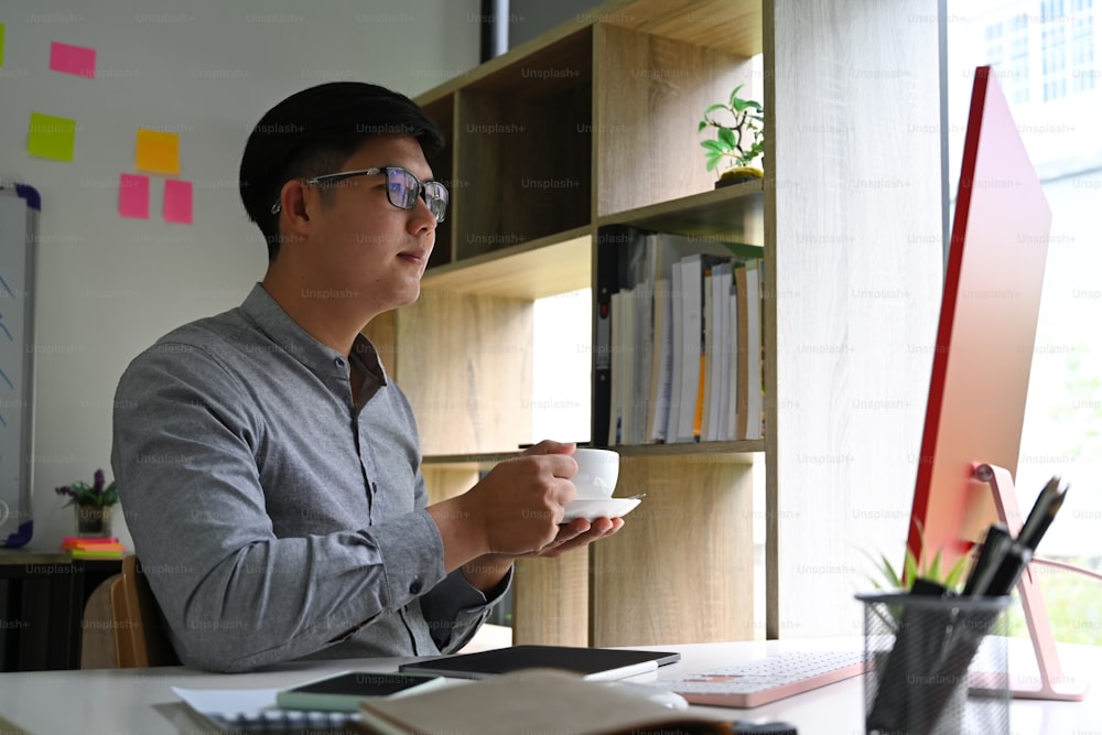 Handsome businessman drinking coffee cup and working with computer.