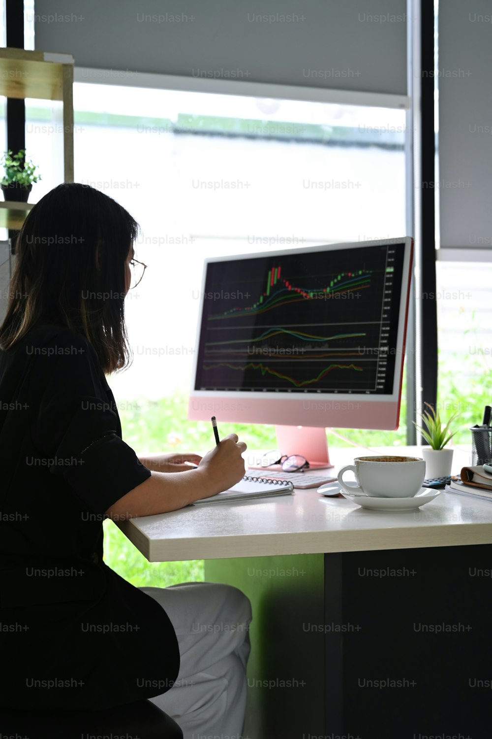 コンピュータの緑色の上で投資チャートを分析する横から見たビジネスウーマン。