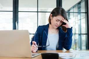 Tried businesswoman young office worker at desk while trying to work in modern office.