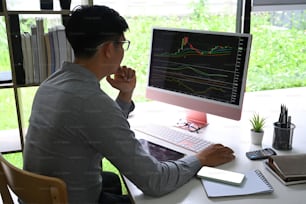 Uomo d'affari che analizza l'investimento del mercato azionario sul computer in ufficio.