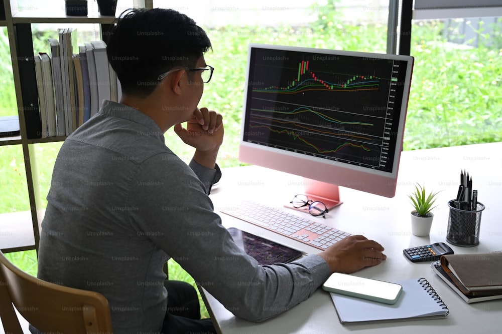 Homme d’affaires analysant l’investissement boursier sur un ordinateur au bureau.