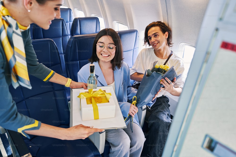 Jovem de alto astral de óculos e seu namorado sorridente recebendo presentes de uma companhia aérea