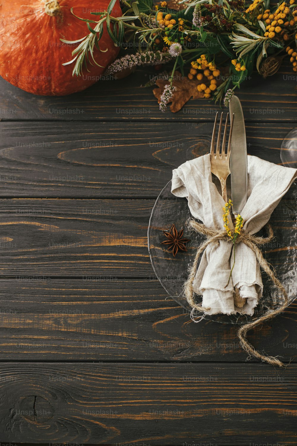 Moderner Teller mit Vintage-Besteck, Leinenserviette, Kräuter auf Holztisch mit Kürbissen und Herbstblumenarrangement. Rustikale Bauernhaushochzeit. Thanksgiving-Tischdekoration