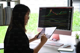 Side view businesswoman analyzing stock market investment with digital tablet.