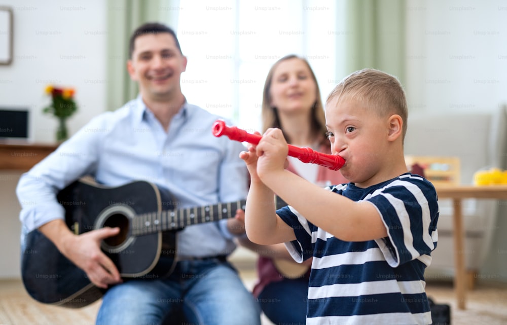 A cheerful down syndrome boy with parents playing musical instruments, laughing.