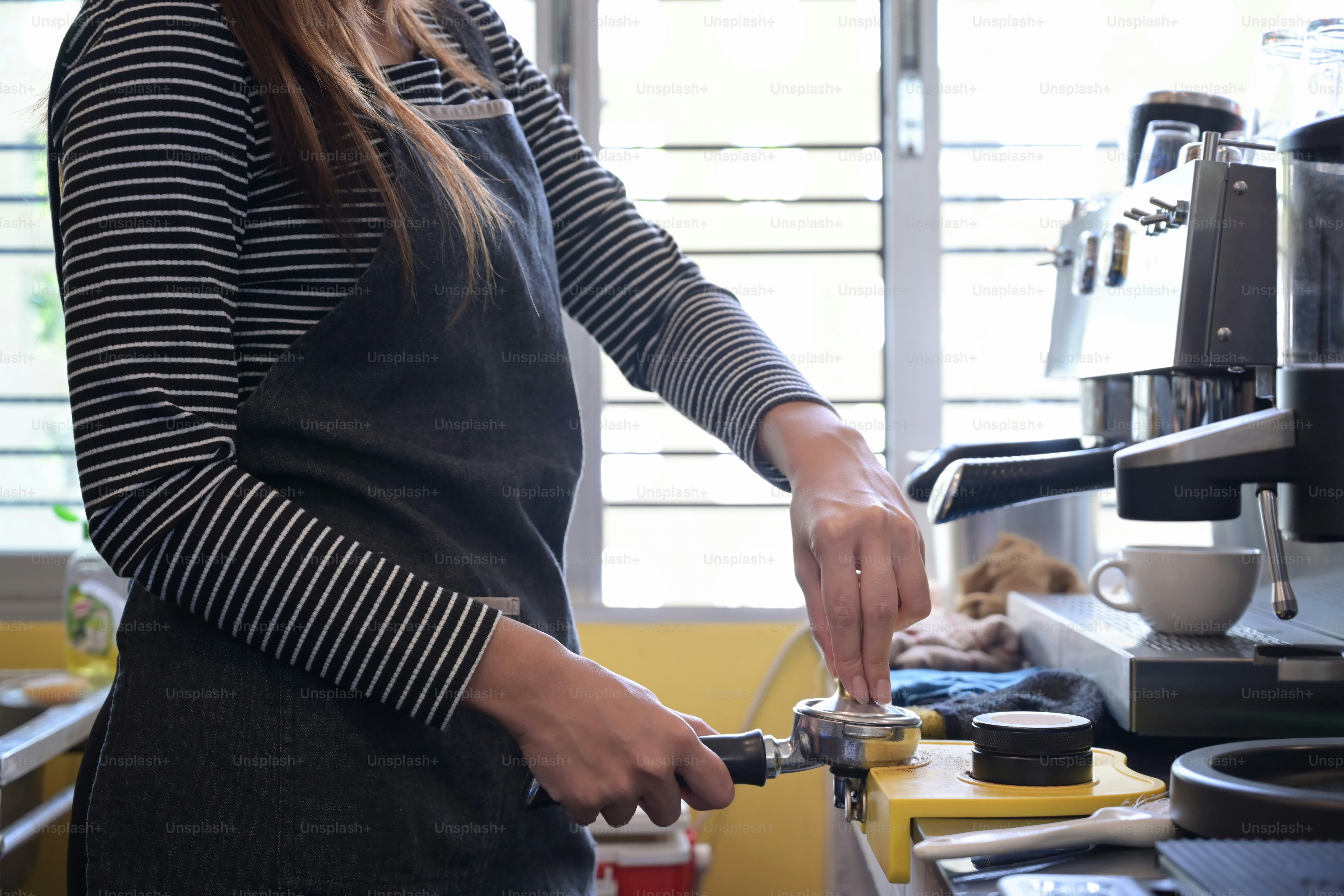 Cropped shot female barista preparing coffee with coffee machine.
