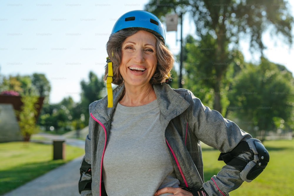 Happy mature woman rollerblading in the park wearing helmet, protective helmet, knee pads, elbow pads