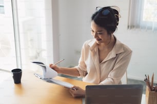 Mujer de negocios asiática analizando el informe de negocios con una computadora portátil en la oficina