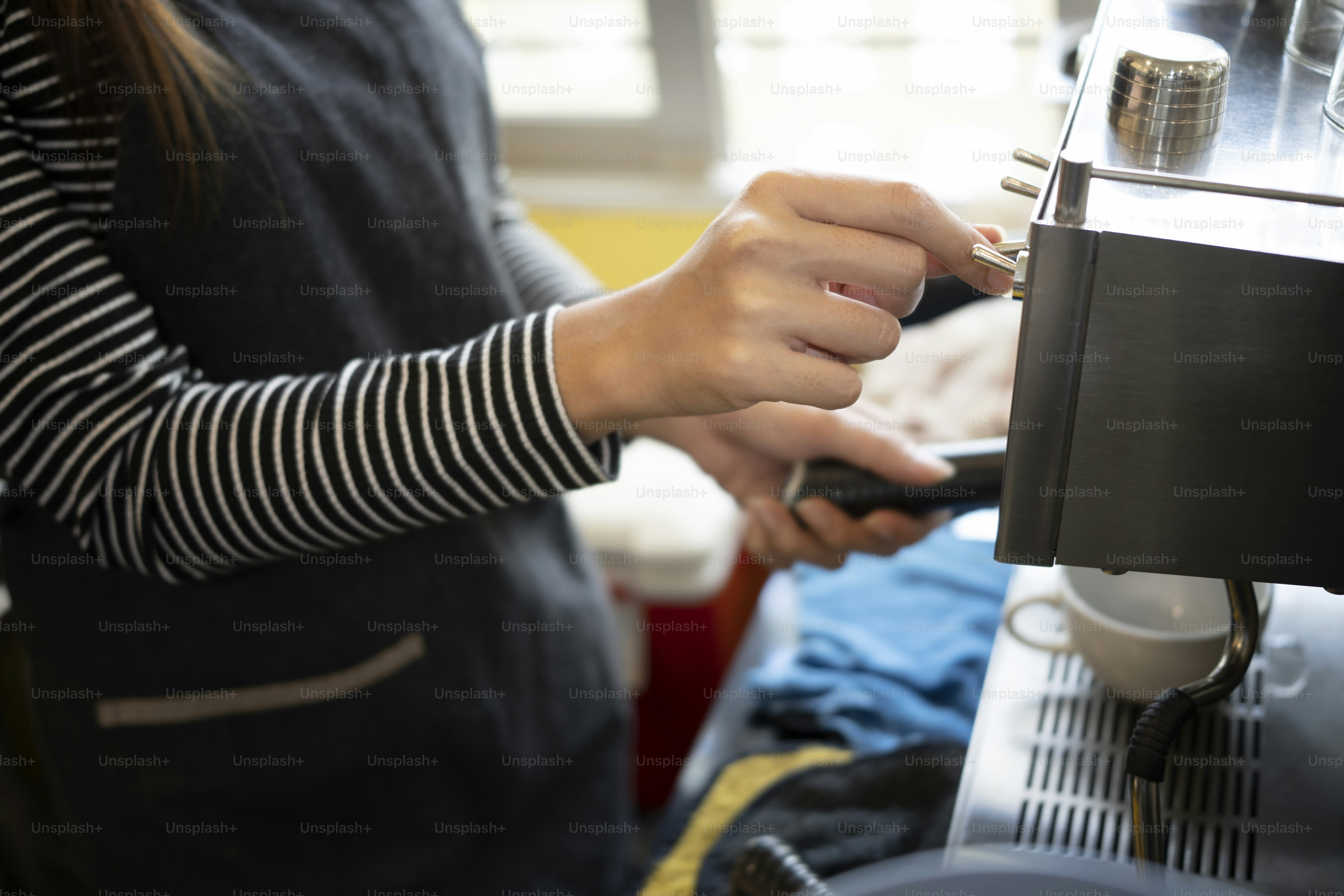 Cropped shot barista preparing coffee with coffee machine.