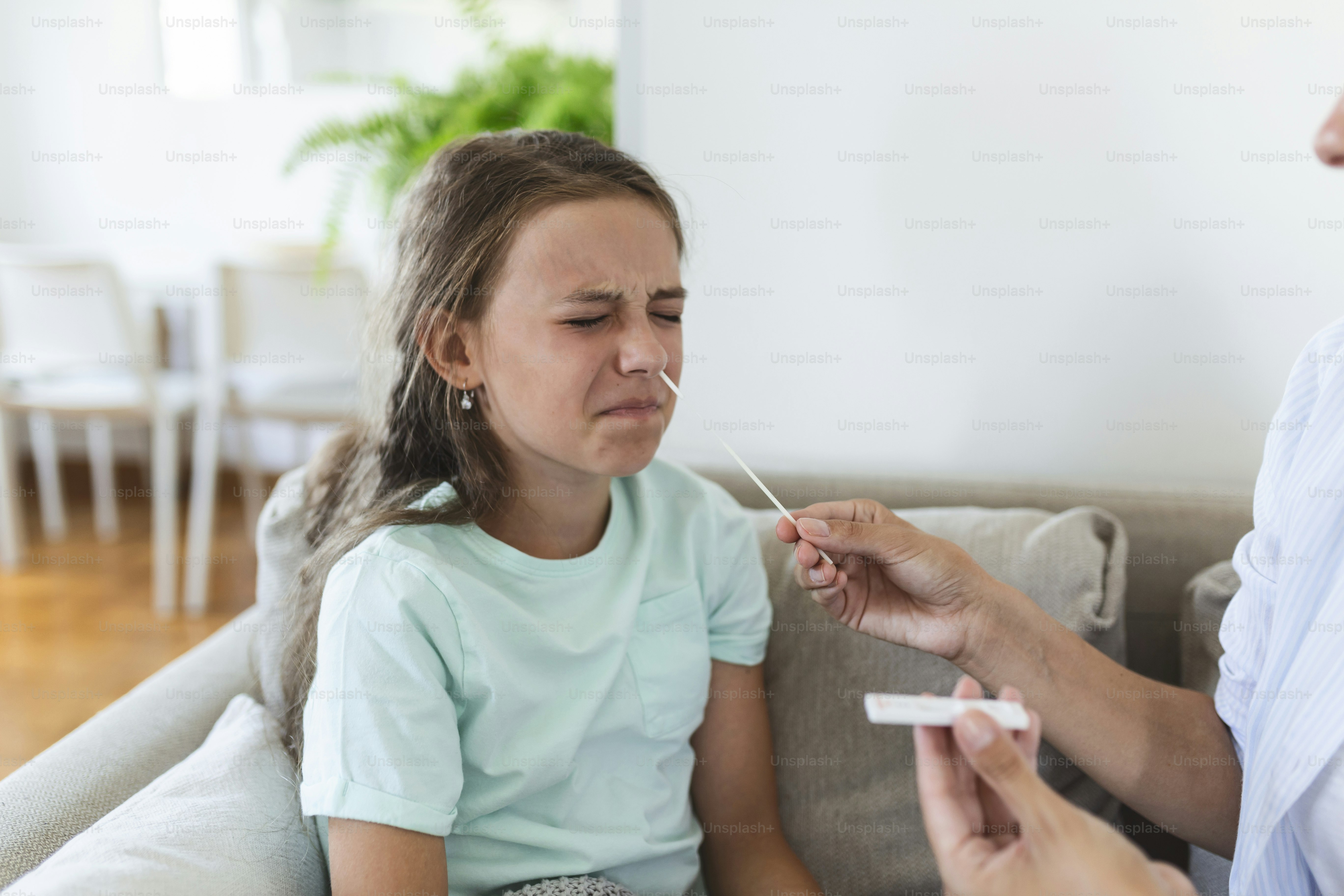 Mother is taking rapid covid-19 test at home to her sick daughter at home. Mom testing young girl for coronavirus infection taking rapid COVID-19 test