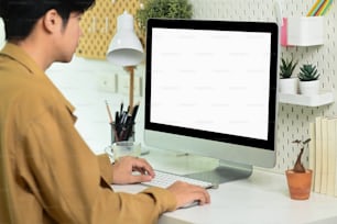 Vista lateral Hombre asiático que trabaja con la computadora en el lugar de trabajo moderno.