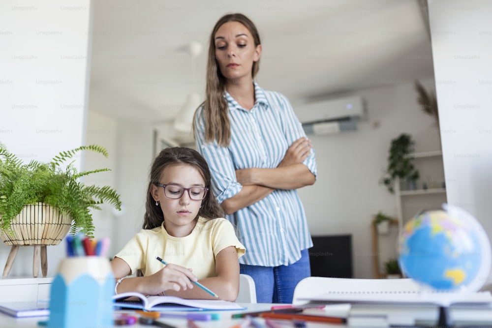 宿題をしている間に集中力に問題がある子供。ストレスを感じている母と娘は、宿題の失敗、学校の問題にイライラしています。母は難しい宿題で彼女の娘を助けます