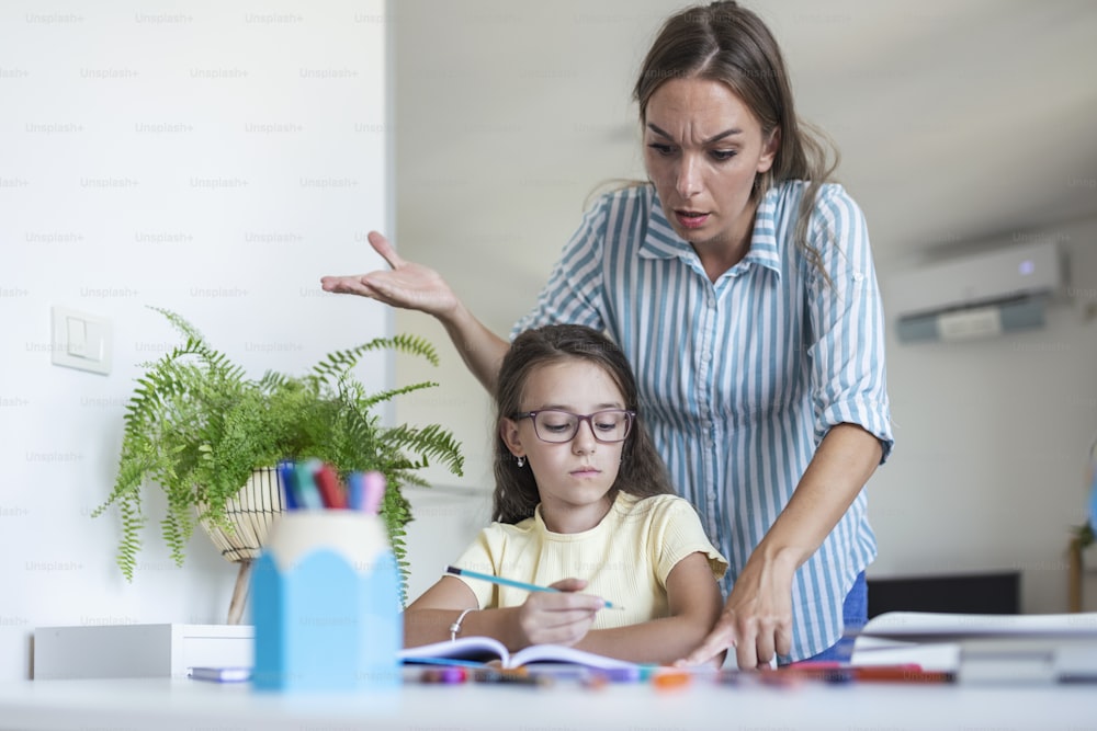 Stressed mother and son frustrated over failure homework, school problems concept. Sad little girl turned away from mother, does not want to do boring homework