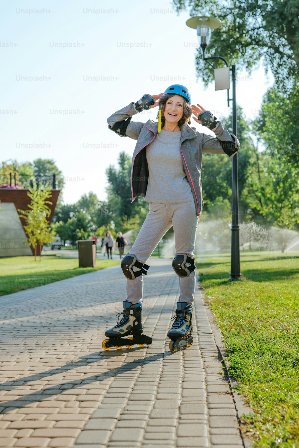 Happy mature woman rollerblading in the park wearing helmet, protective helmet, knee pads, elbow pads