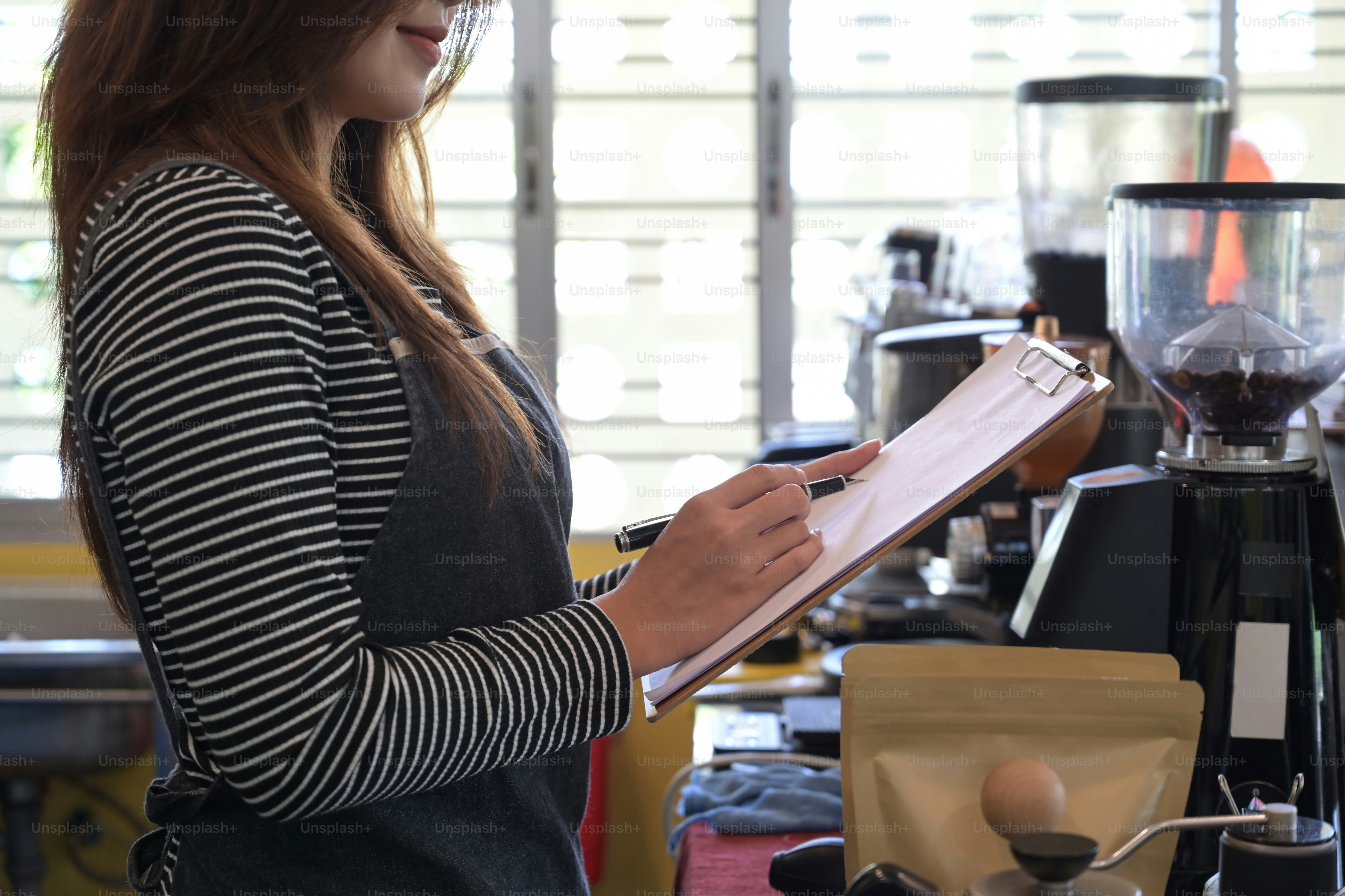 Female barista taking order from customer at counter in coffee shop.