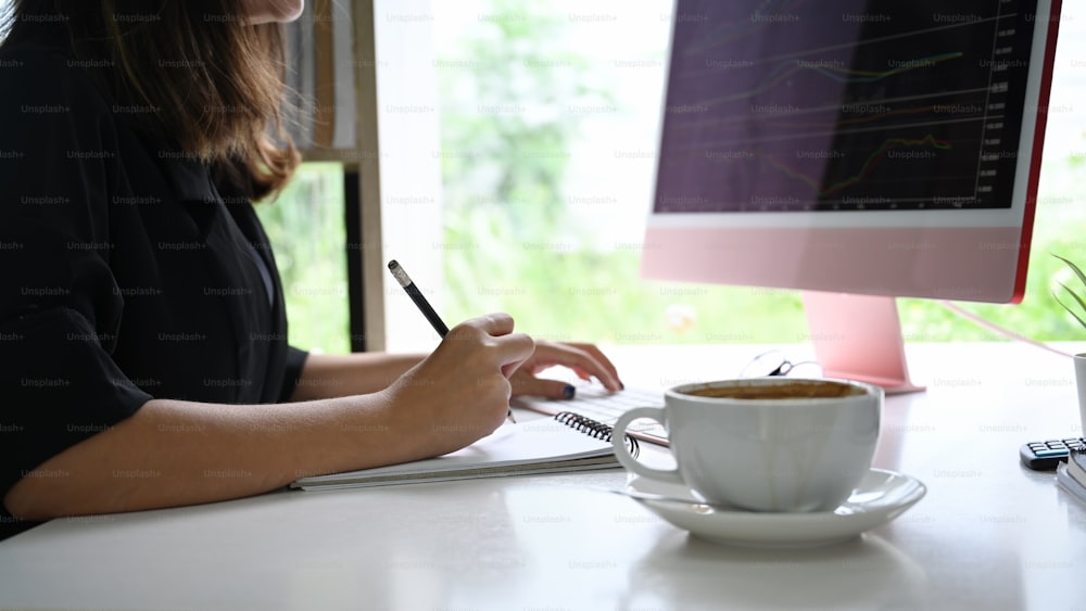 Mujer de negocios comprobando el mercado de valores en una computadora de escritorio.