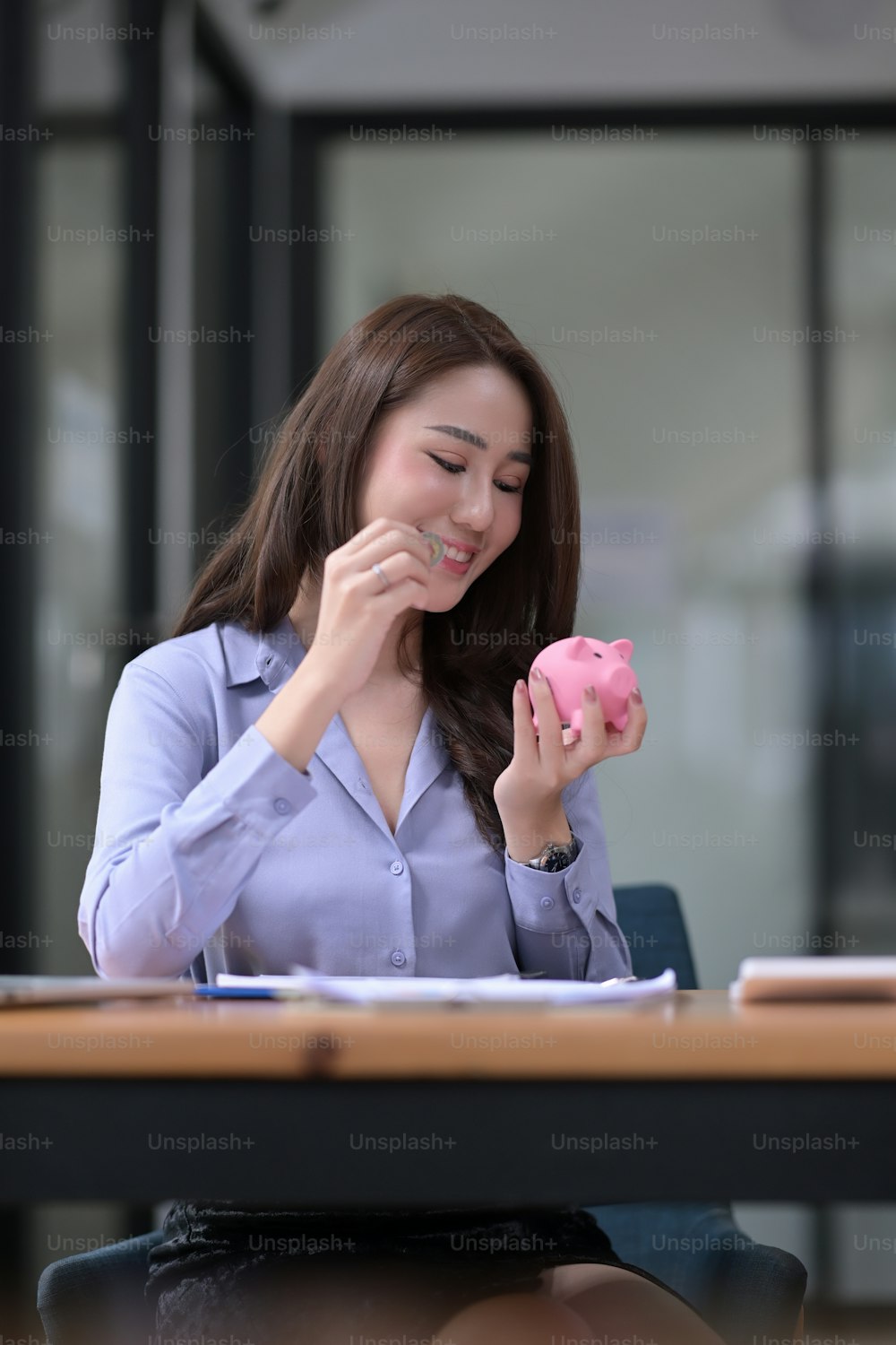 Beautiful Asian woman putting coin into piggy bank. Wealth and financial concept.