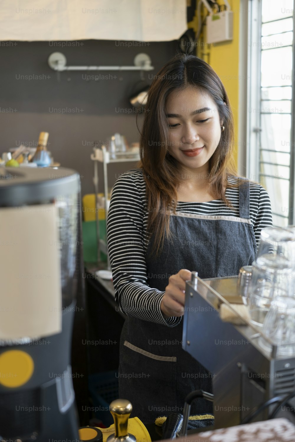 Asian woman barista preparing coffee for customer in cafe bar.
