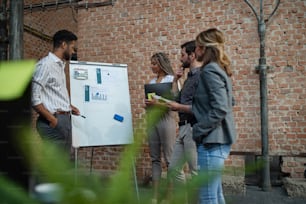 Cheerful young businesspeople standing and working in office, a cooperation and brainstorming concept.