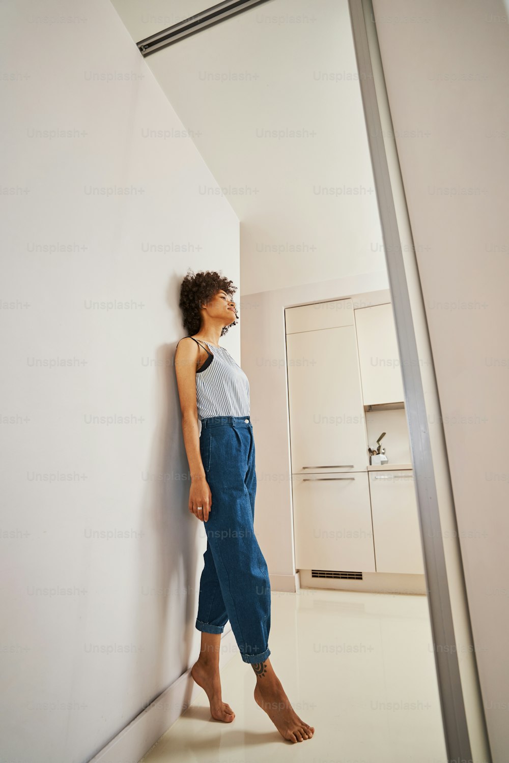 Side view of a slender calm lady dressed in casual clothes standing on tiptoe in the corridor