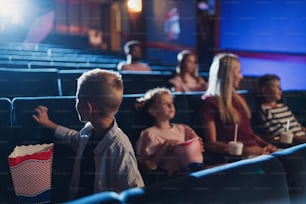 映画館で映画を見ながら幸せな小さな子供を持つ母親。