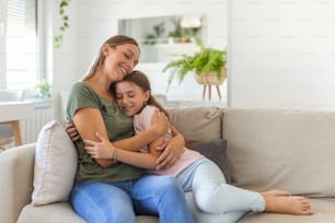 I love you so much. Portrait of happy young mother piggybacking cute smiling little daughter in living room, affectionate school age girl embracing beloved millennial female nanny or foster mom