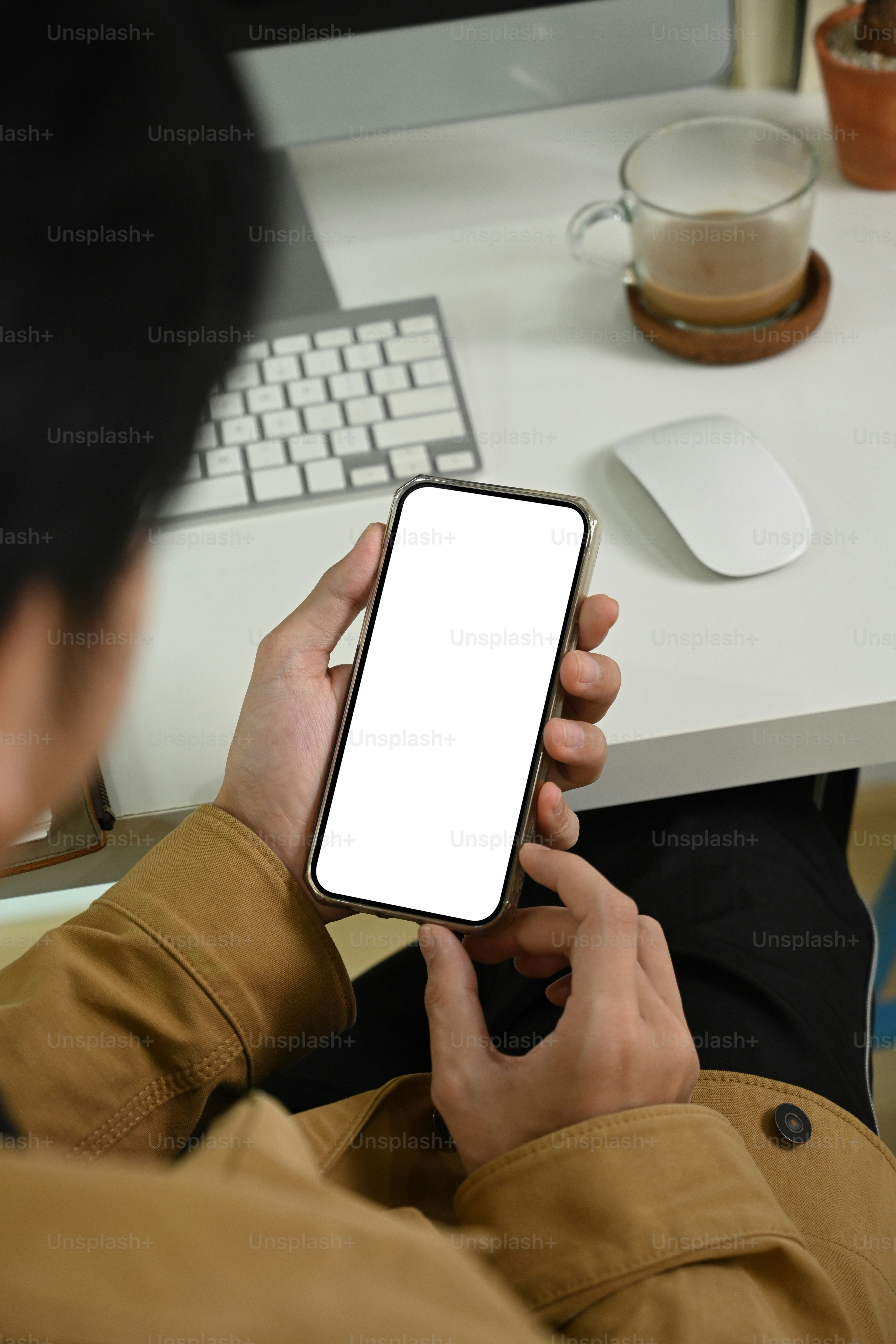 Young man sitting at workplace and using smart phone.