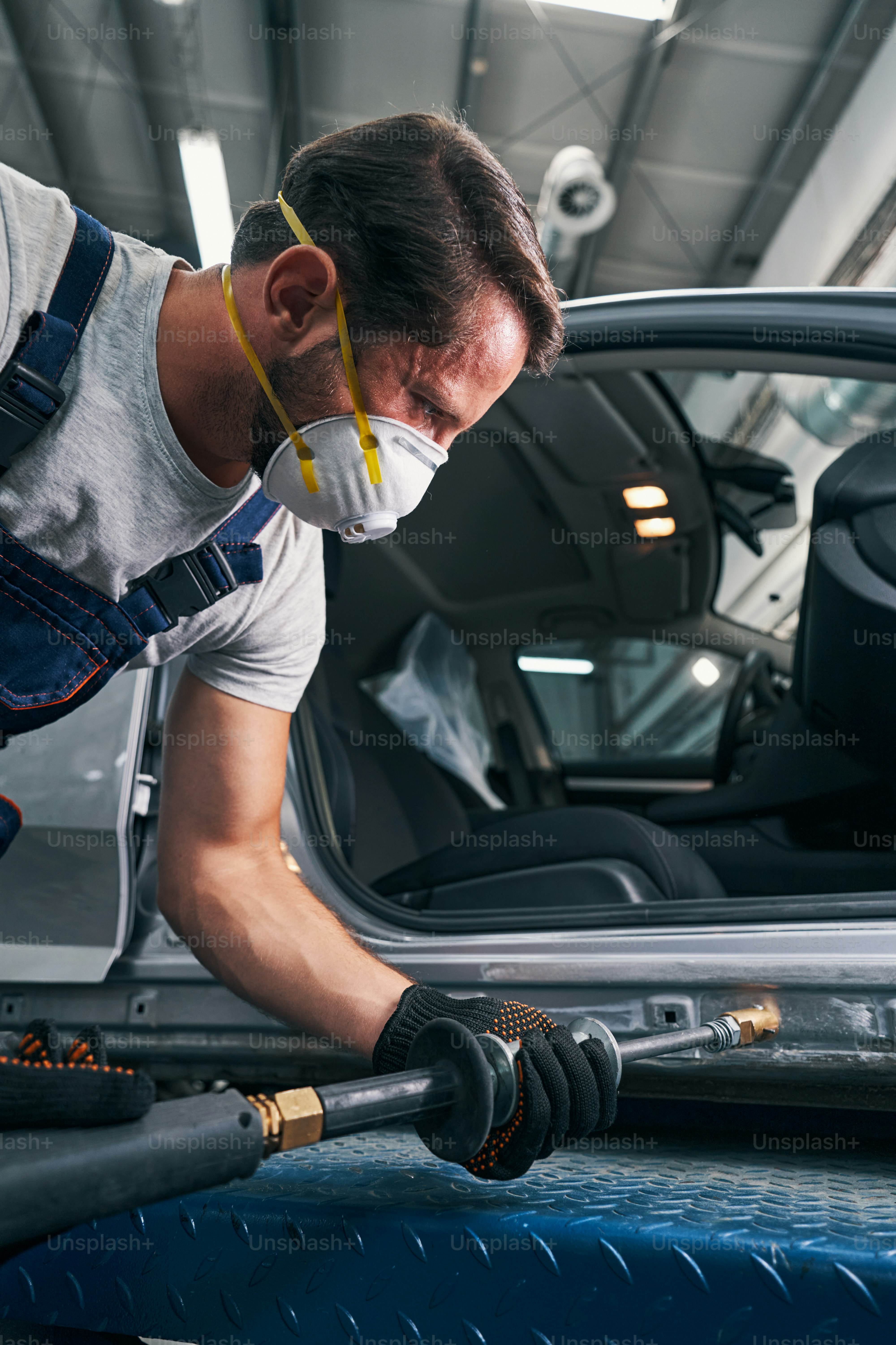 Autobody repair service technician straightening side door body surface with peening slide hammer