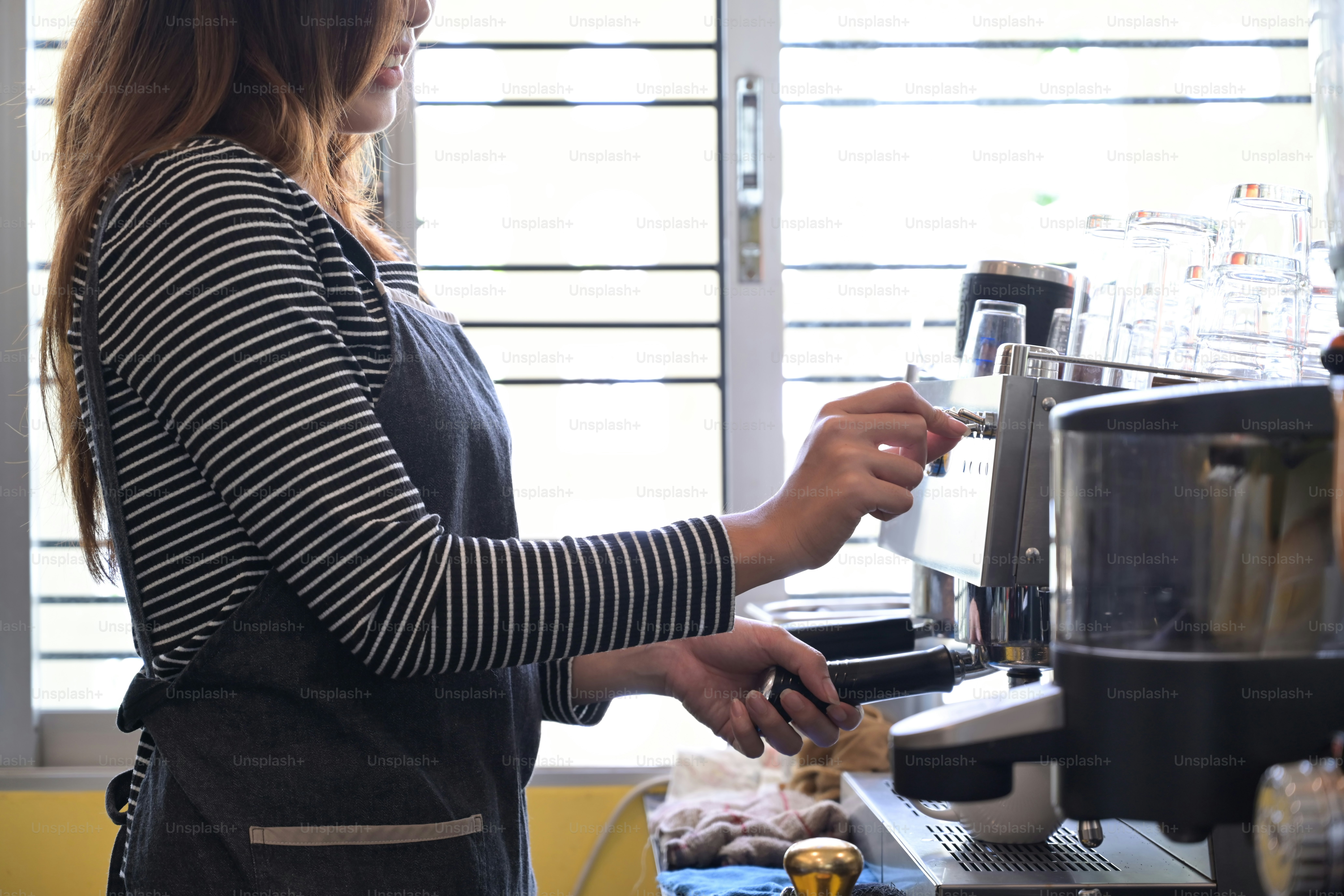 Female barista preparing coffee with coffee machine.