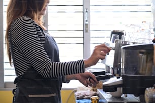 Barista feminina que prepara café com máquina de café.