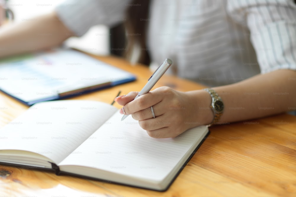 Close up, Empresária escrevendo estratégia de negócios em caderno no escritório, caderno em branco, segurando caneta, tomando notas, organizando agenda