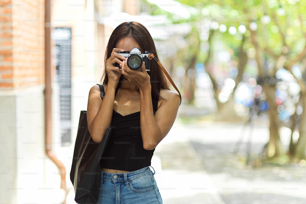 Fotógrafa turística femenina que toma fotos de la ciudad vieja con una cámara vintage, capturando las vacaciones, el pasatiempo hipster y la actividad