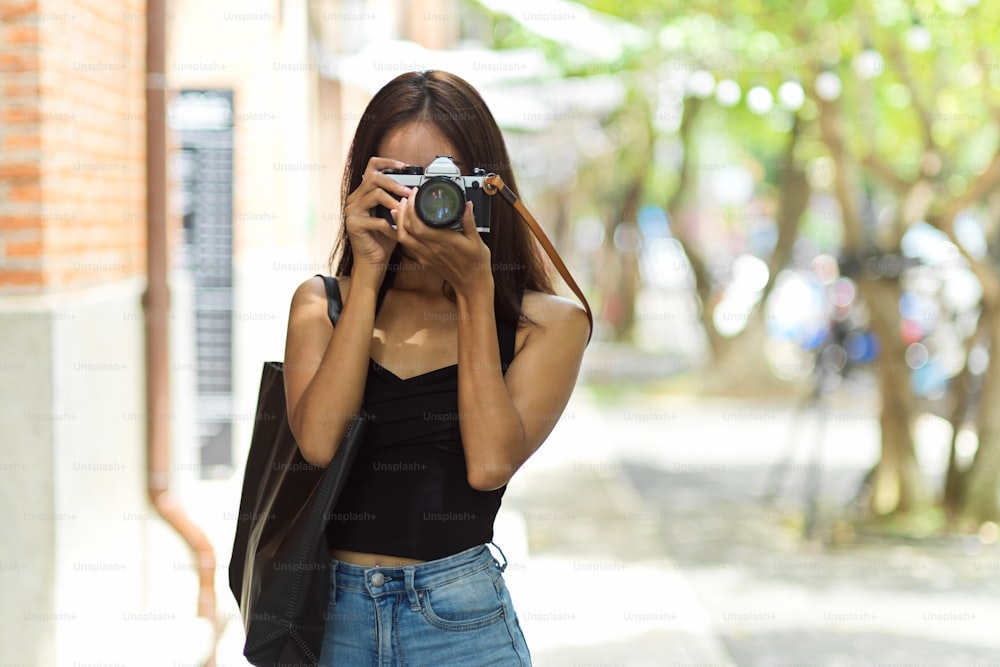 Photographe touristique féminine prenant des photos de la vieille ville avec un appareil photo vintage, capturant les vacances, le passe-temps et l’activité hipster