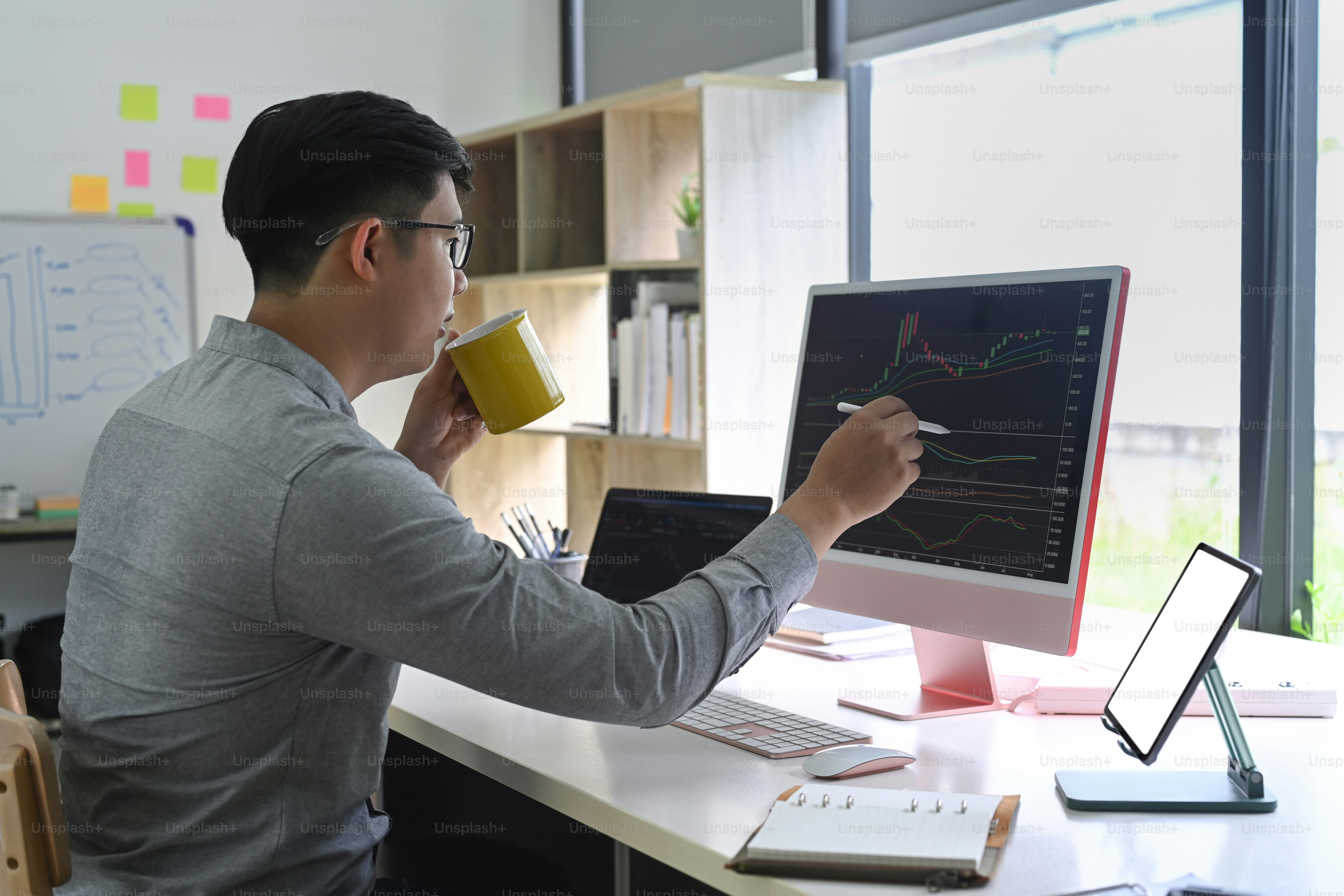 Vista lateral del hombre de negocios que comprueba el mercado de valores en una computadora de escritorio en su oficina.