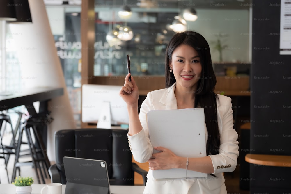 Smiling asian business woman looking at camera and working in her office.