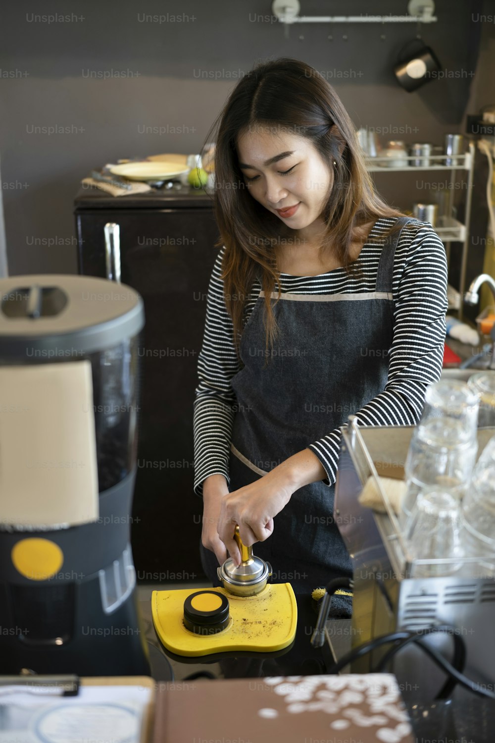 Female barista in apron preparing coffee while at the bar in cafe.