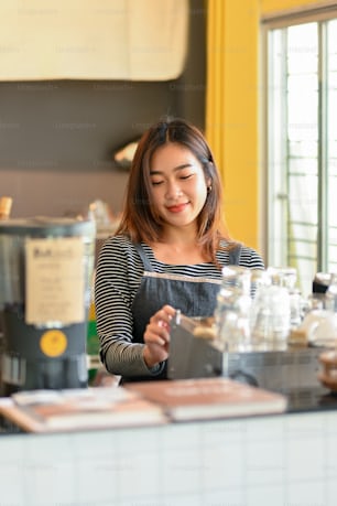 Portrait of Charming asian female barista making coffee with coffee machine at coffee shop, coffee brewing