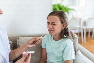 Mother performing nasal swab on her child taking example to analyze if patient is positive for the infectious diseas