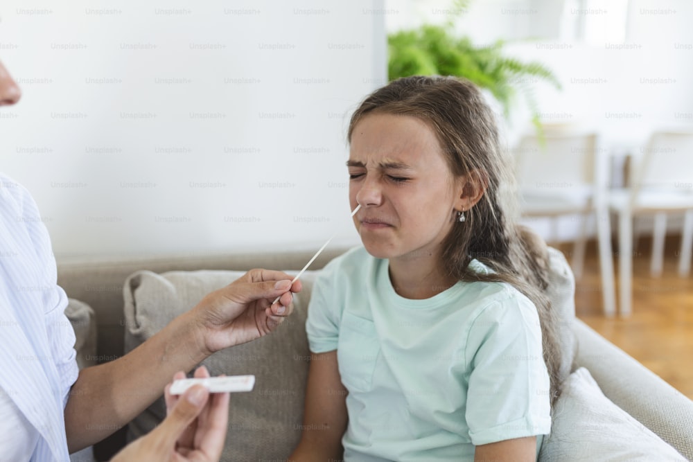 Mother performing nasal swab on her child taking example to analyze if patient is positive for the infectious diseas