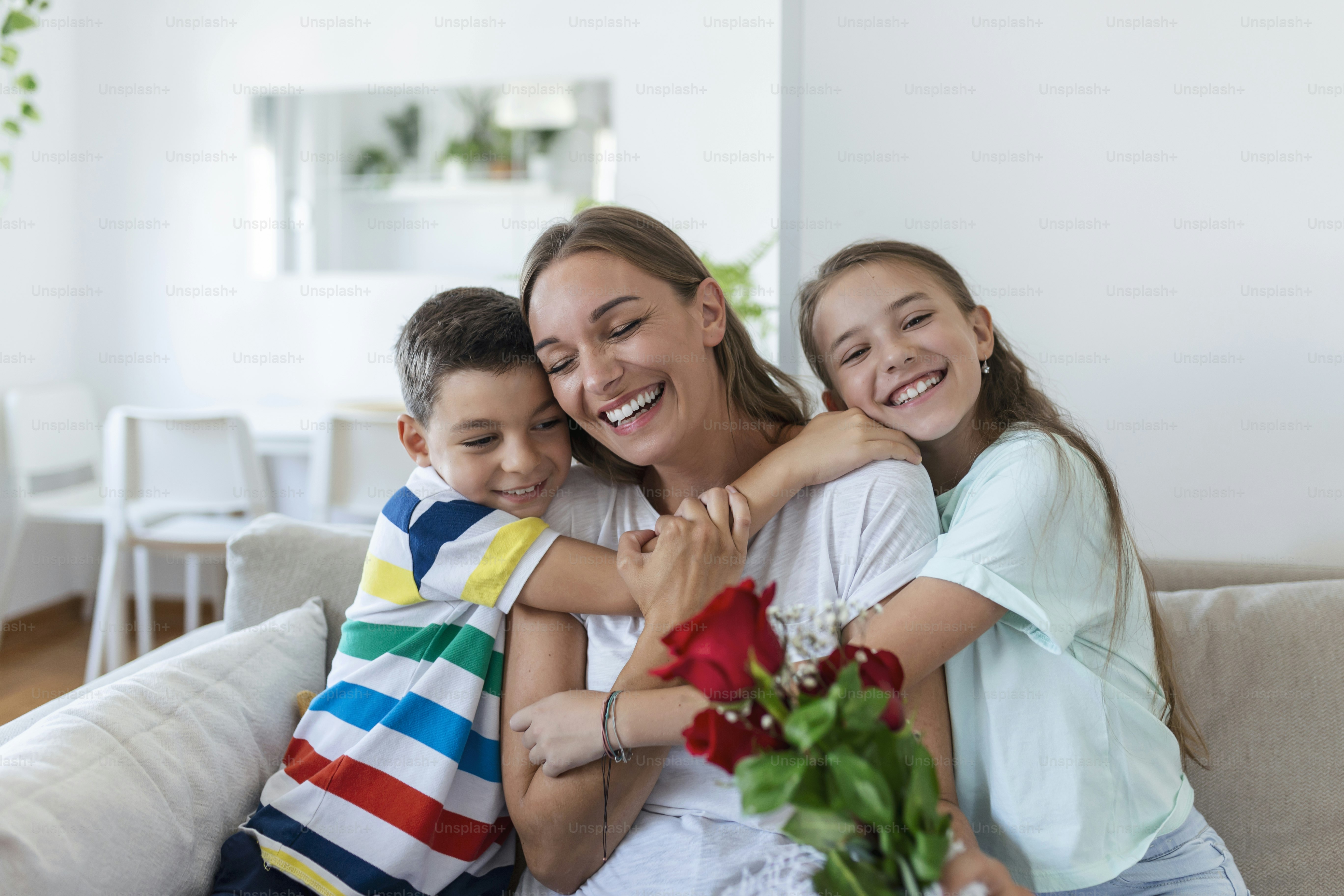Foto Una joven madre con un ramo de rosas se ríe, abraza a su hijo y ...