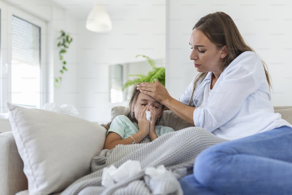 Mãe medindo a temperatura de seu filho doente. Criança doente com febre alta deitada na cama e mãe segurando termômetro. Mão na testa.