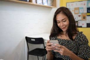Smiling female using mobile phone in coffee shop.