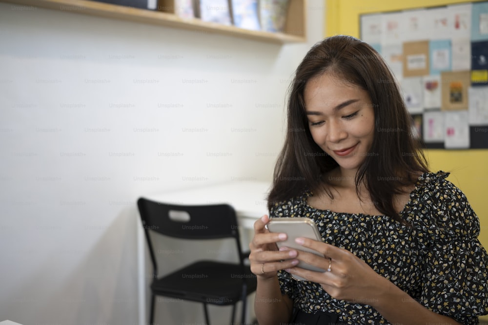 Smiling female using mobile phone in coffee shop.
