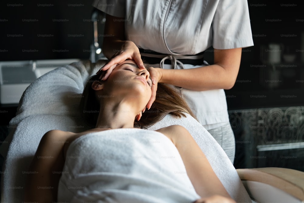 Mujer relajante que tiene terapia de masaje en el salón del spa