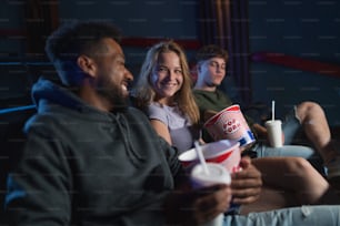 Una alegre pareja joven con palomitas de maíz en el cine, hablando.