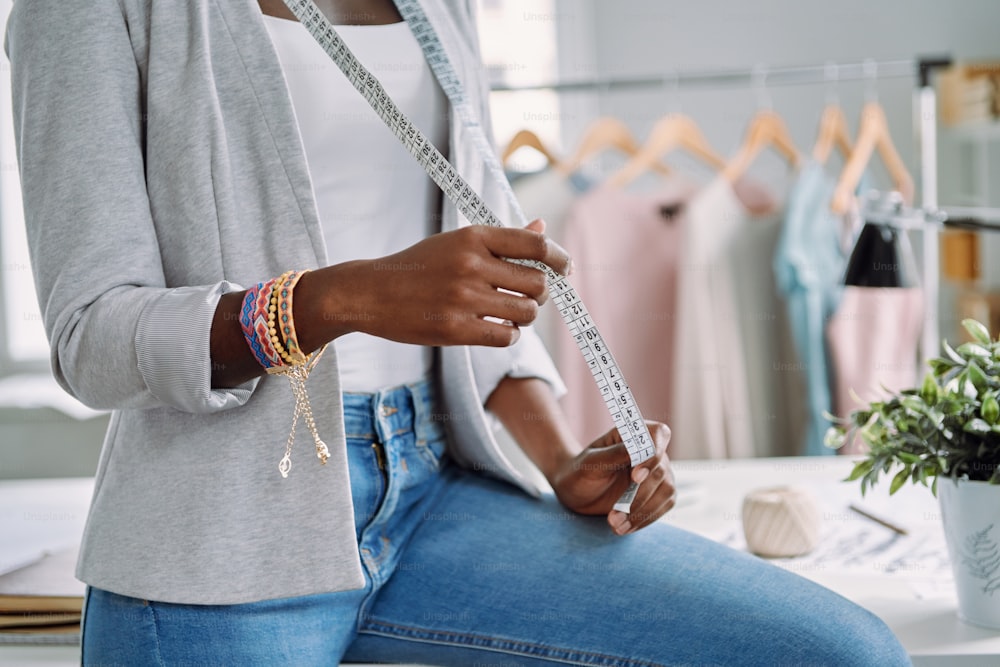 Close-up of African woman carrying tape measure while working in design studio