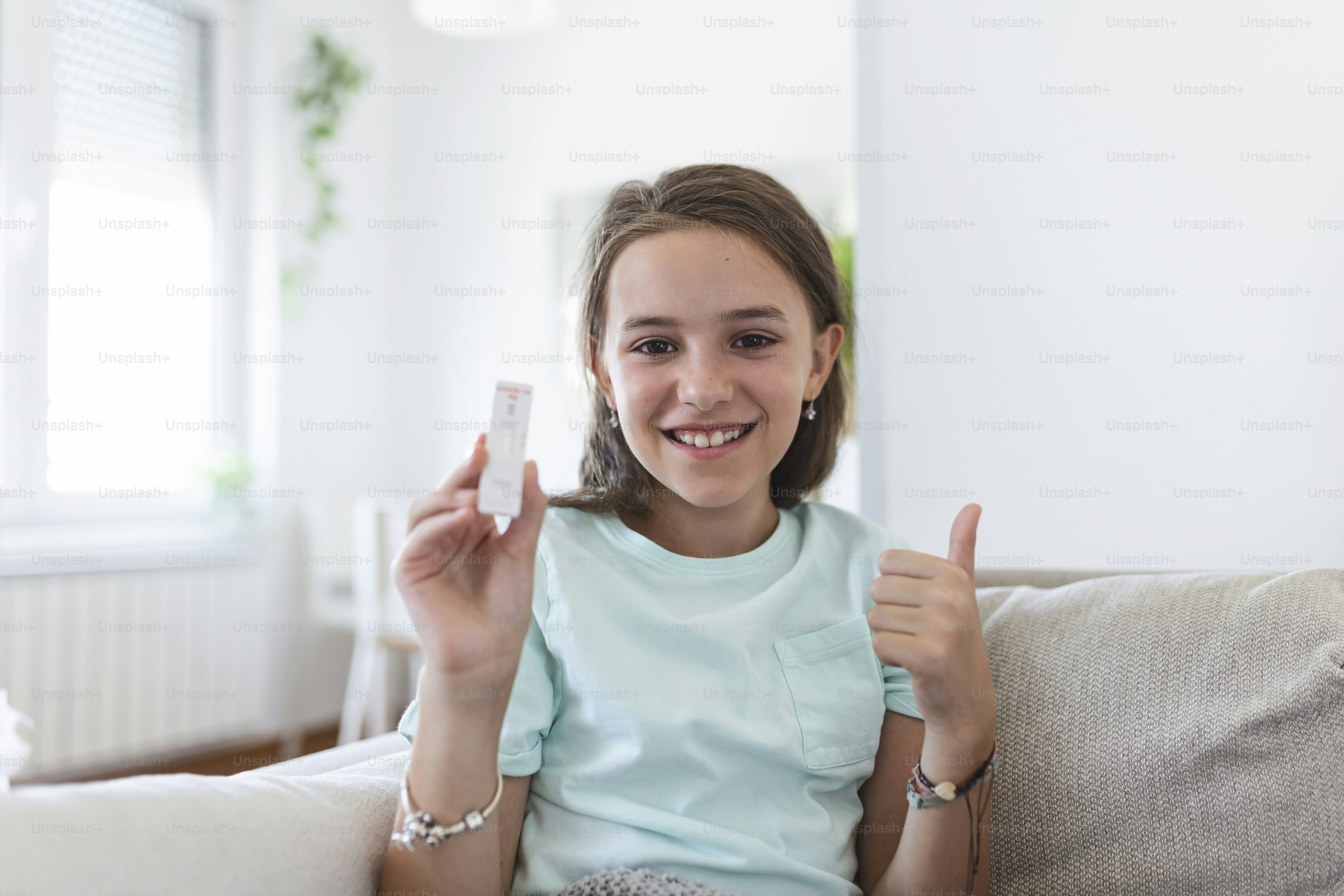 Close-up shot of little girl holding a negative test device. Happy young girl showing her negative Coronavirus - Covid-19 rapid test. Coronavirus