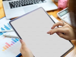 Closeup, top view, businesswoman, female accountant using digital tablet, working on tablet, tablet blank screen mockup, office supplies in background
