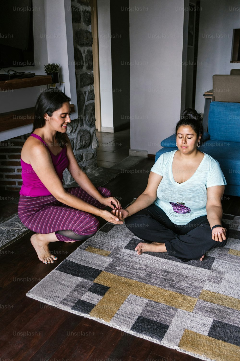 Curvy mexican woman practicing yoga with instructor at home in Latin America