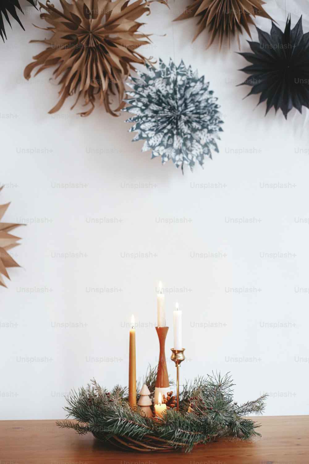 Elegante coroa de Natal com velas e decorações na mesa de madeira no fundo da parede branca com estrelas de papel suecas. Tempo de inverno atmosférico. Advento natalino, hygge festivo escandinavo